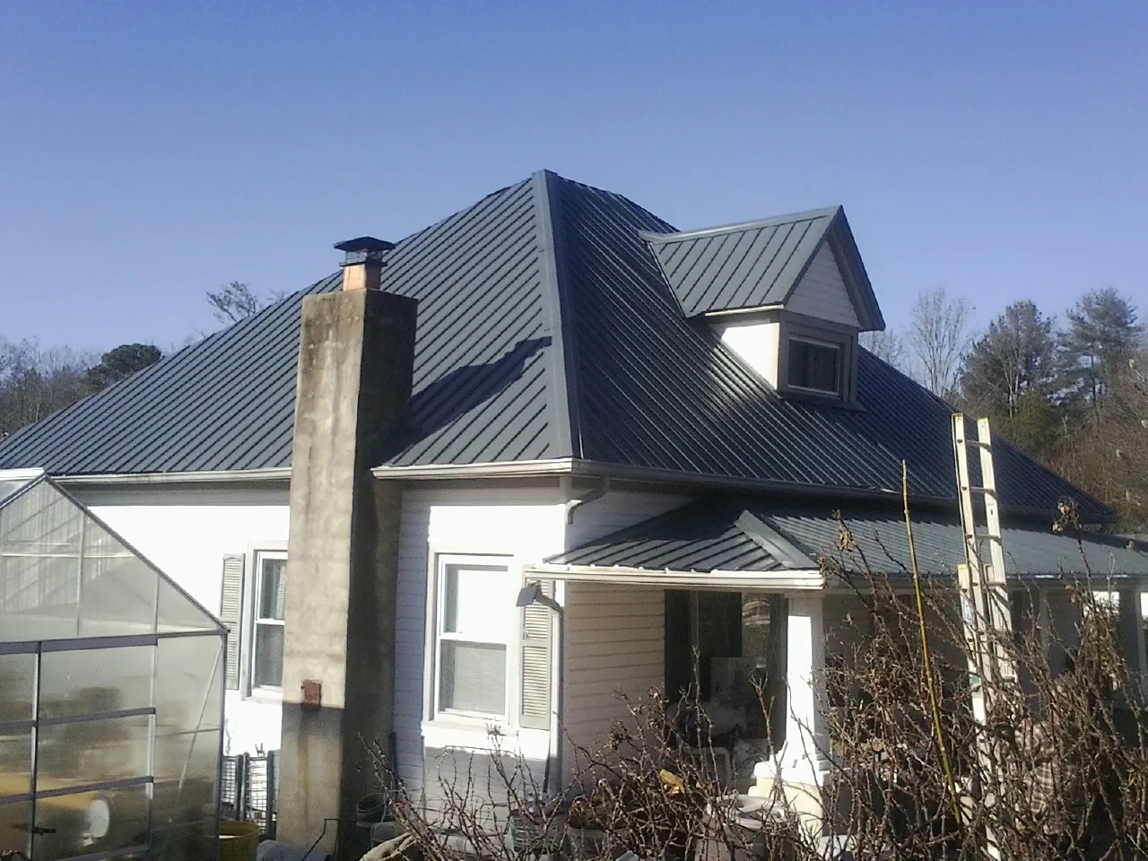 Dark blue standing seam metal roof on a white farmhouse with dormer — Slate & Tile Roof Repair by Roofing Brothers in Libertyville