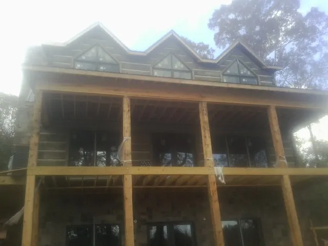 Dormers and porch framing on a large log home under construction — Roof Coating work by our crew in Libertyville