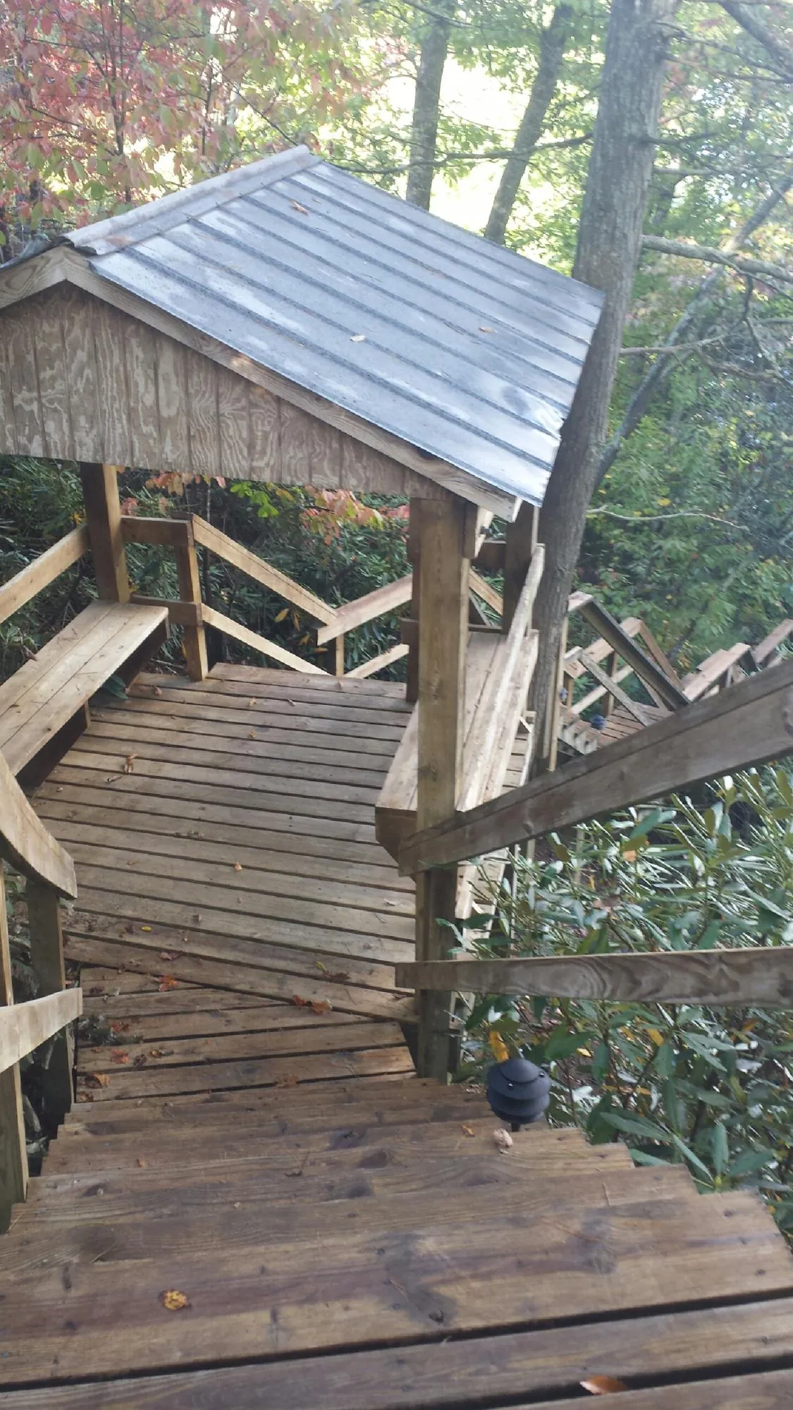 Metal roofed shelter over wooden steps on a wooded walkway — Skylight Repair & Installation work by our crew in Libertyville