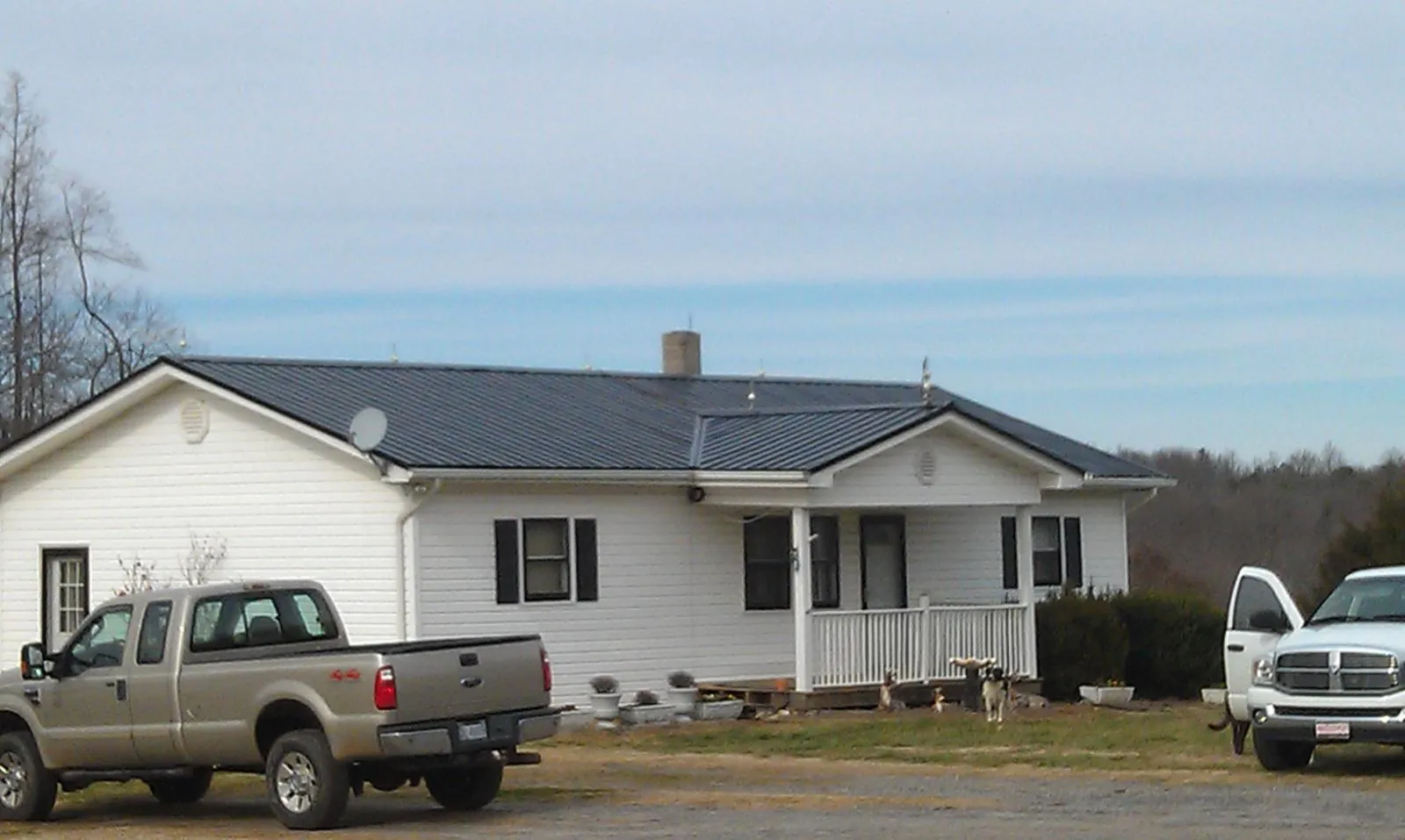 Finished dark metal roof on a white ranch home with work trucks parked in Libertyville