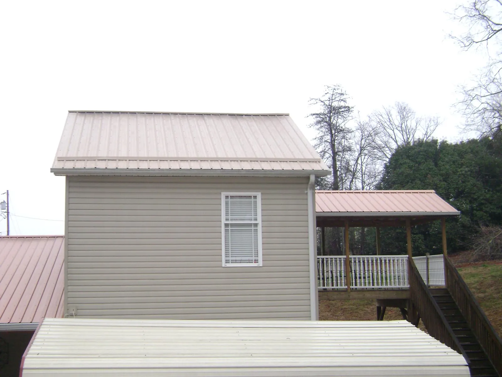 Tan metal roofs on a two story addition and attached porch, from a Roof Replacement job in Libertyville
