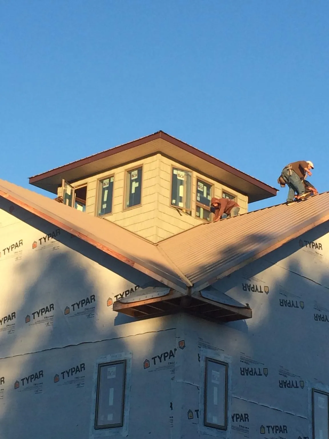 Roofers working around a rooftop cupola on a new metal roof at sunset — Roof Waterproofing in Libertyville by Roofing Brothers